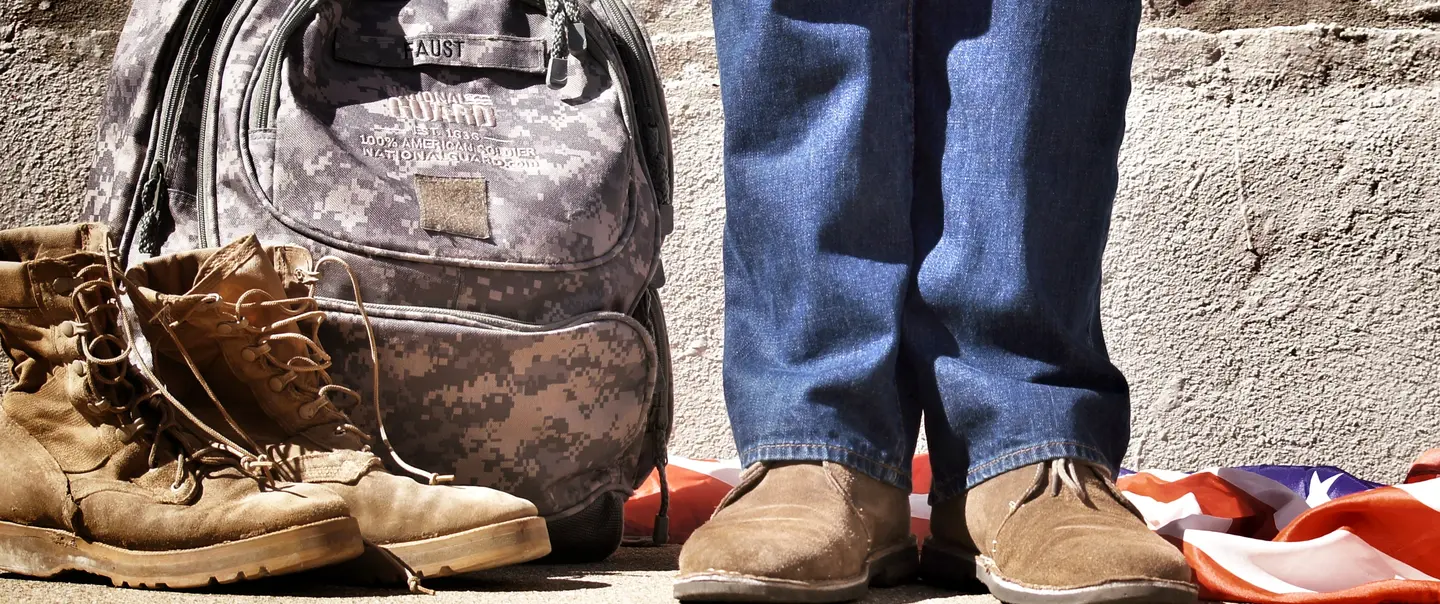 Veteran returning home, showing shoes, backpack and flag