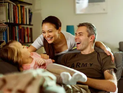Family with Dad wearing army shirt, Mom, and daughter, in living room